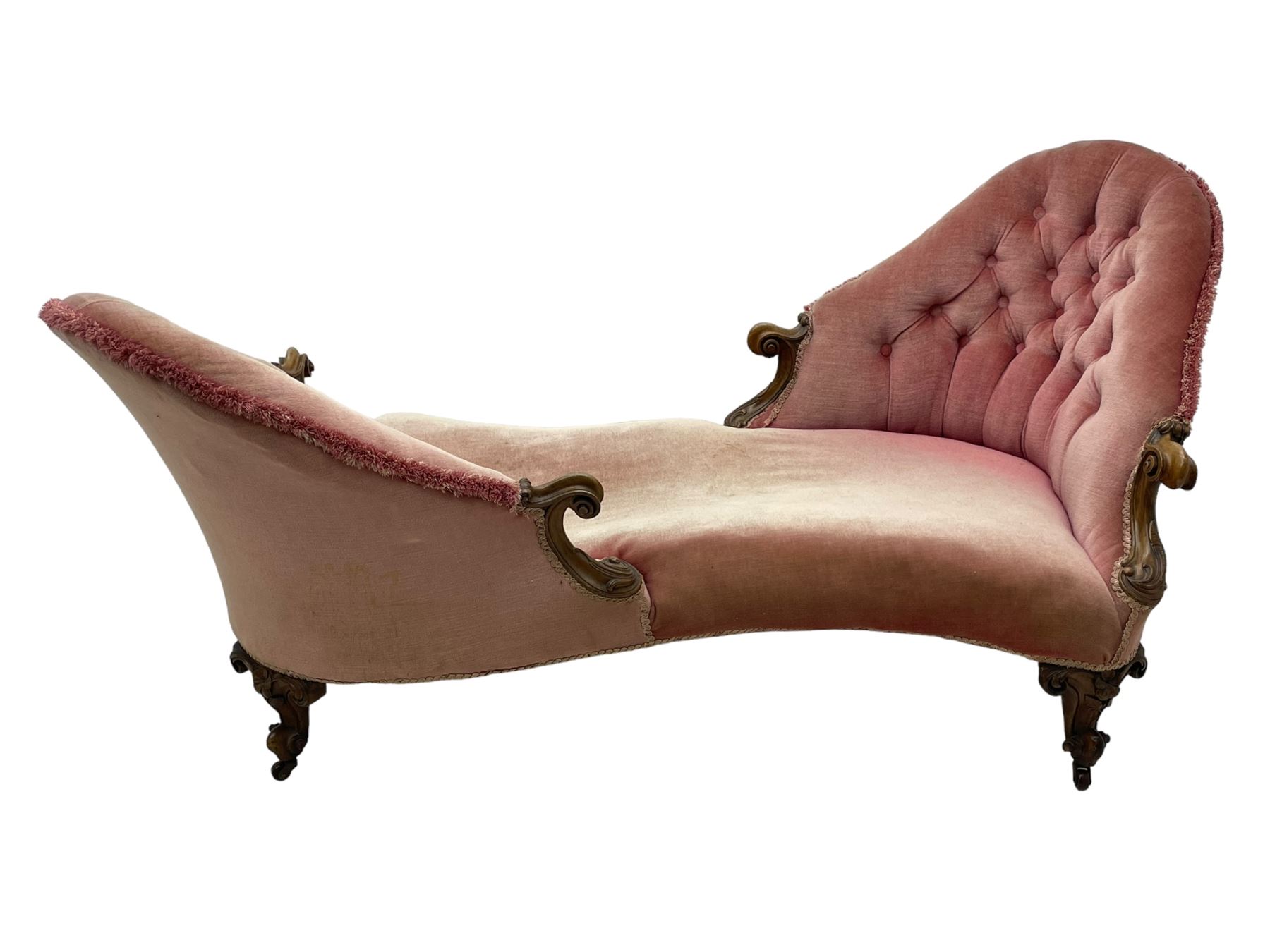 Victorian walnut framed tete-a-tete loveseat, scrolled arm terminals with moulded foliate decoration, buttoned backs and sprung seat upholstered in pale pink velvet, raised on cabriole supports with applied flower heads and scroll feet terminating to ceramic castors