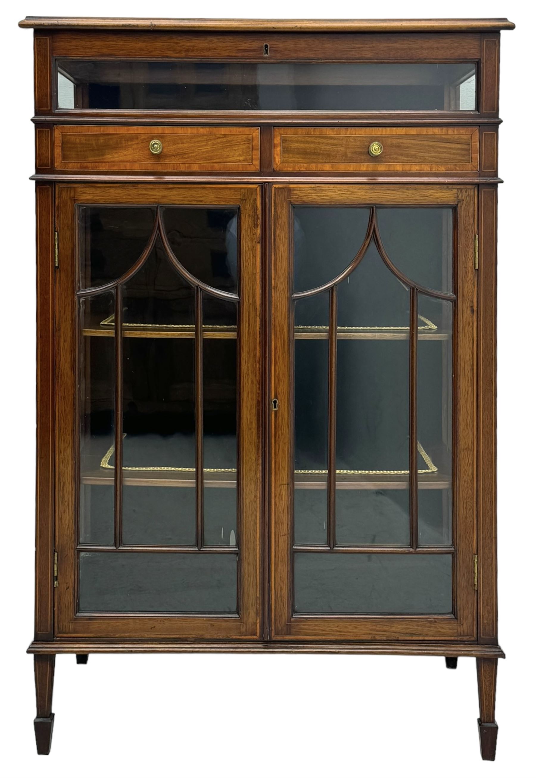 Edwardian mahogany bijouterie display cabinet, featuring satinwood inlay and crossbanding, hinged glazed top fitted with two banded drawers, over two astragal glazed doors enclosing black wool baize lined shelves with gold trim, supported by spade feet