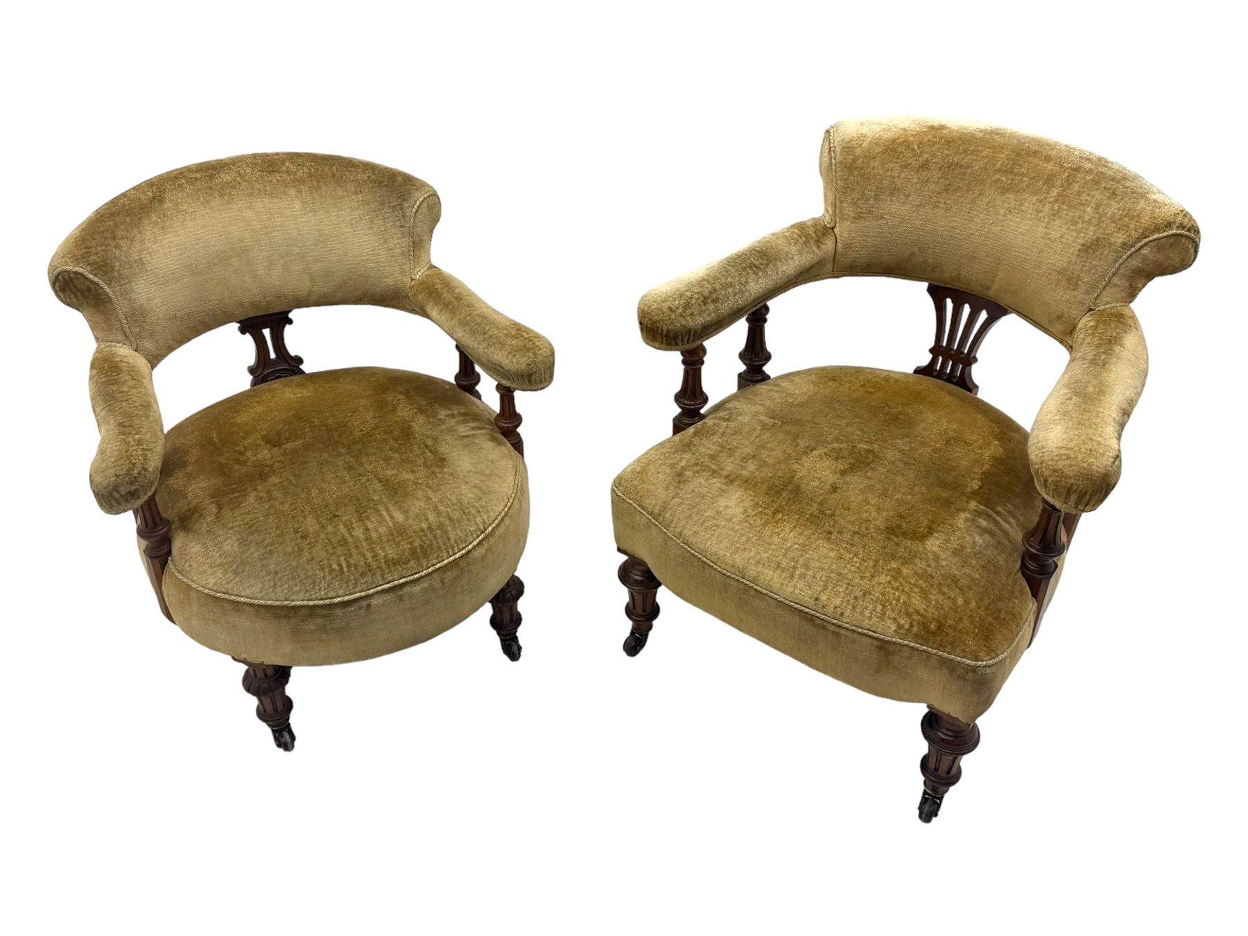 Victorian pair of mahogany armchairs, upholstered in gold velvet fabric, each with curved back, pierced splat and scroll arms, one with rounded seat and the other square, on turned front supports with castors