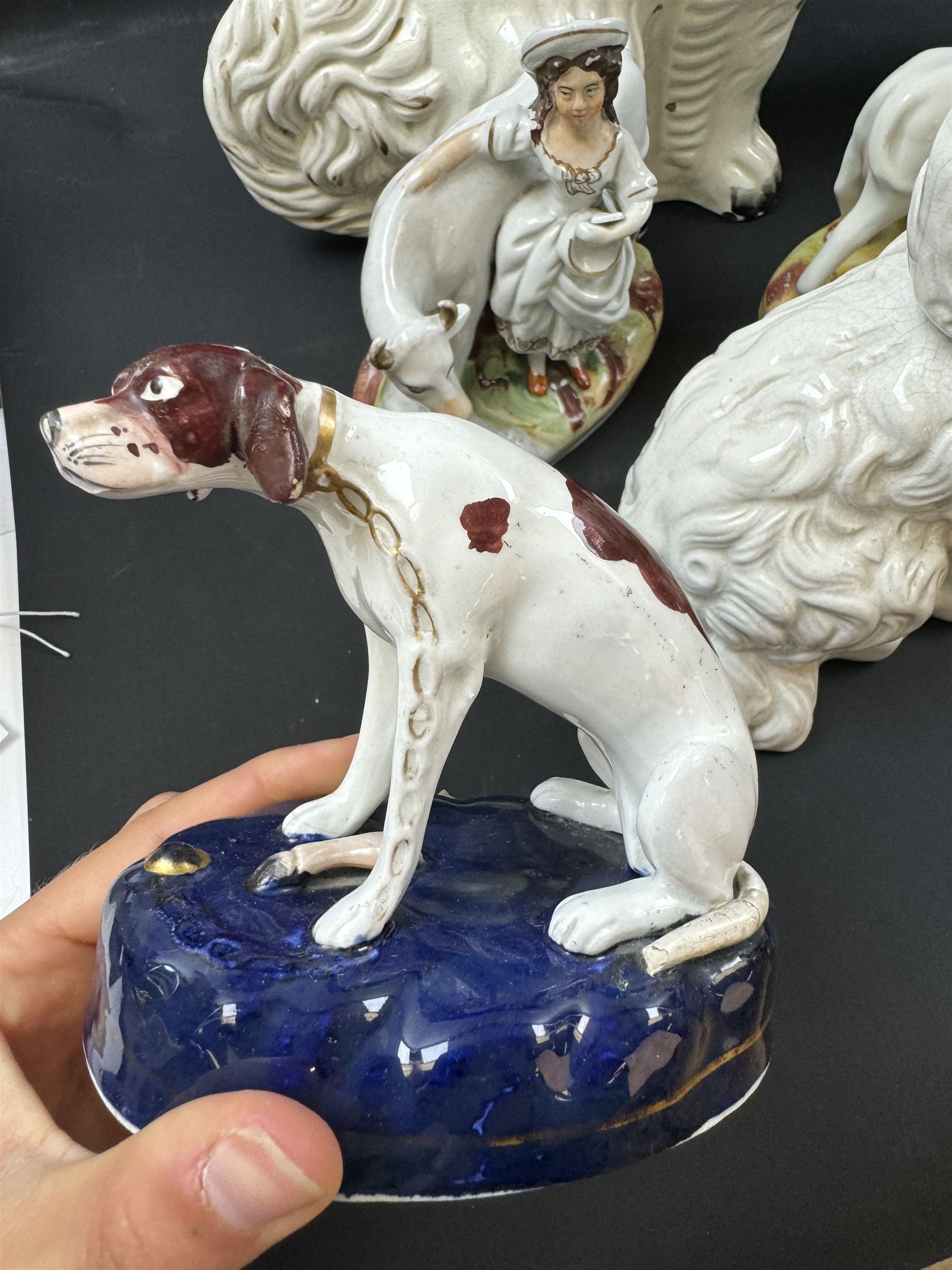 Staffordshire and Staffordshire style figures, to include a chained hound upon a blue oval base in the manner of Samuel Alcock, two pairs of seated Spaniels, a pair modelled as male figure and milk maid with cows, pair of recumbent Greyhounds, etc.