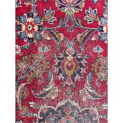 Large Persian Kashan crimson ground carpet, central floral medallion surrounded by swirling leafy branches and palmettes, enclose by floral pattern spandrels, the indigo border with overall scrolling design decorated with palmettes, within guard stripes 