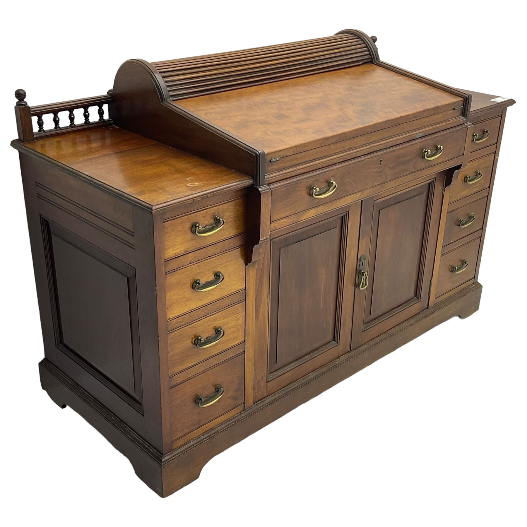 Victorian walnut clerk's desk, raised central section with tambour roll over hinged top, the interior fitted with leather inset writing surfaces, small drawers, document divisions and pen and ink stand, central drawer over double panelled cupboard, flanked by two banks of four graduating drawers, on bracket feet 