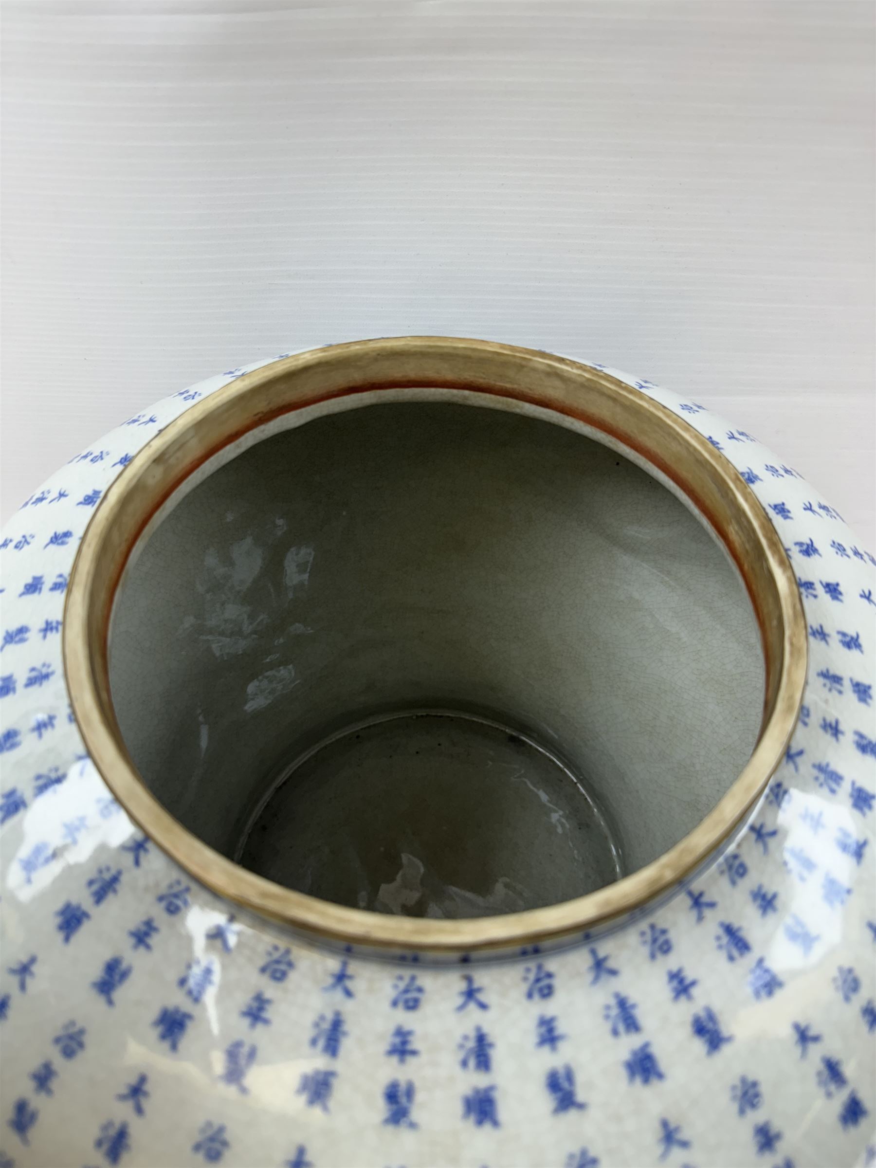 Large Oriental design ginger jar and cover, of squat baluster form with domed cover, decorated in blue with Chinese characters against a white crackle glaze ground, the cover, neck and foot rim with applied brass band, with character mark beneath, H43cm