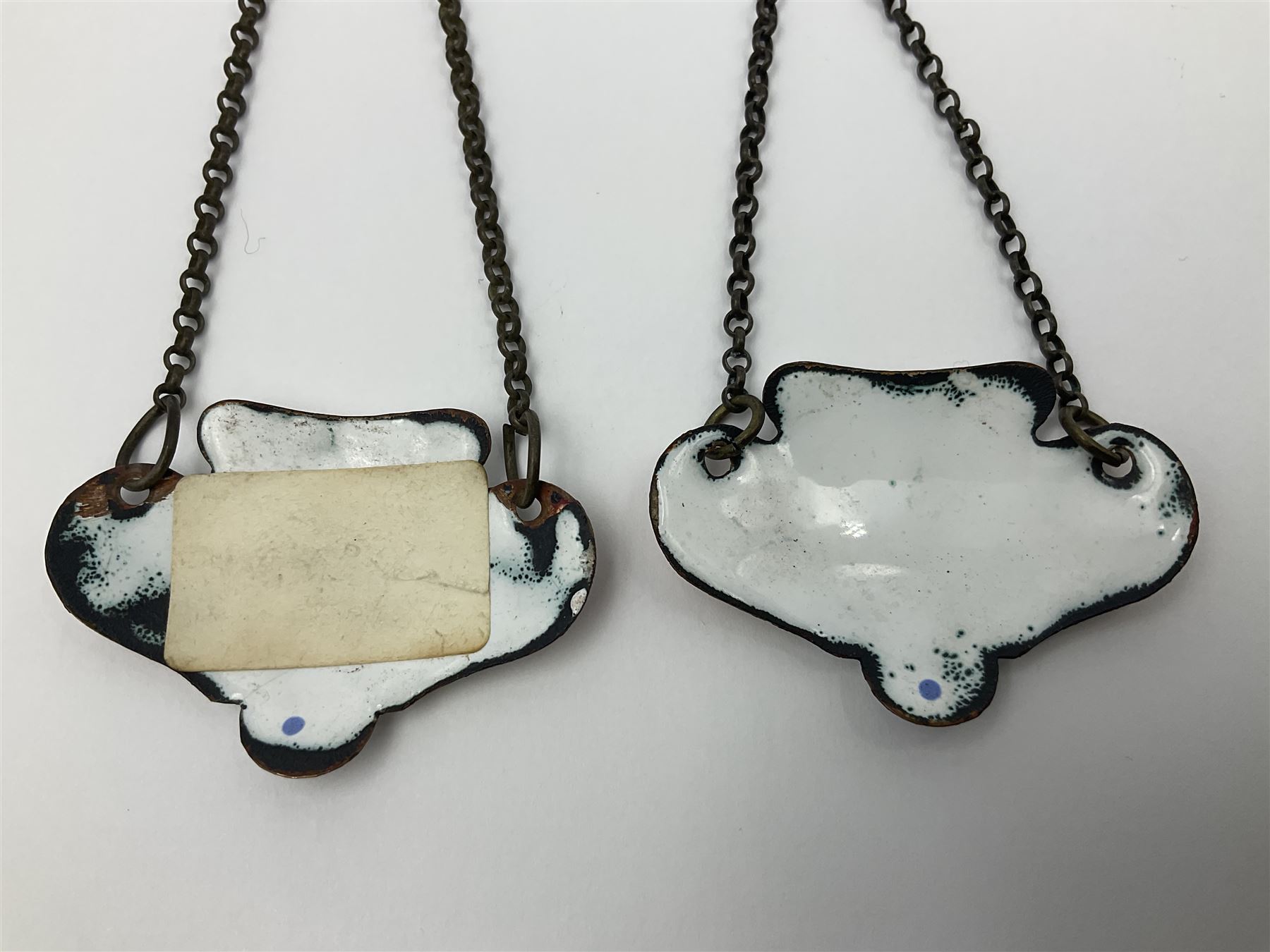 Two late 18th/early 19th century enamel wine labels, each of shaped form, titled 'CLARET', and 'SHERRY' and decorated with floral sprigs and scroll detail upon a white ground, each with suspension chain, each approximately H3.5cm W5cm