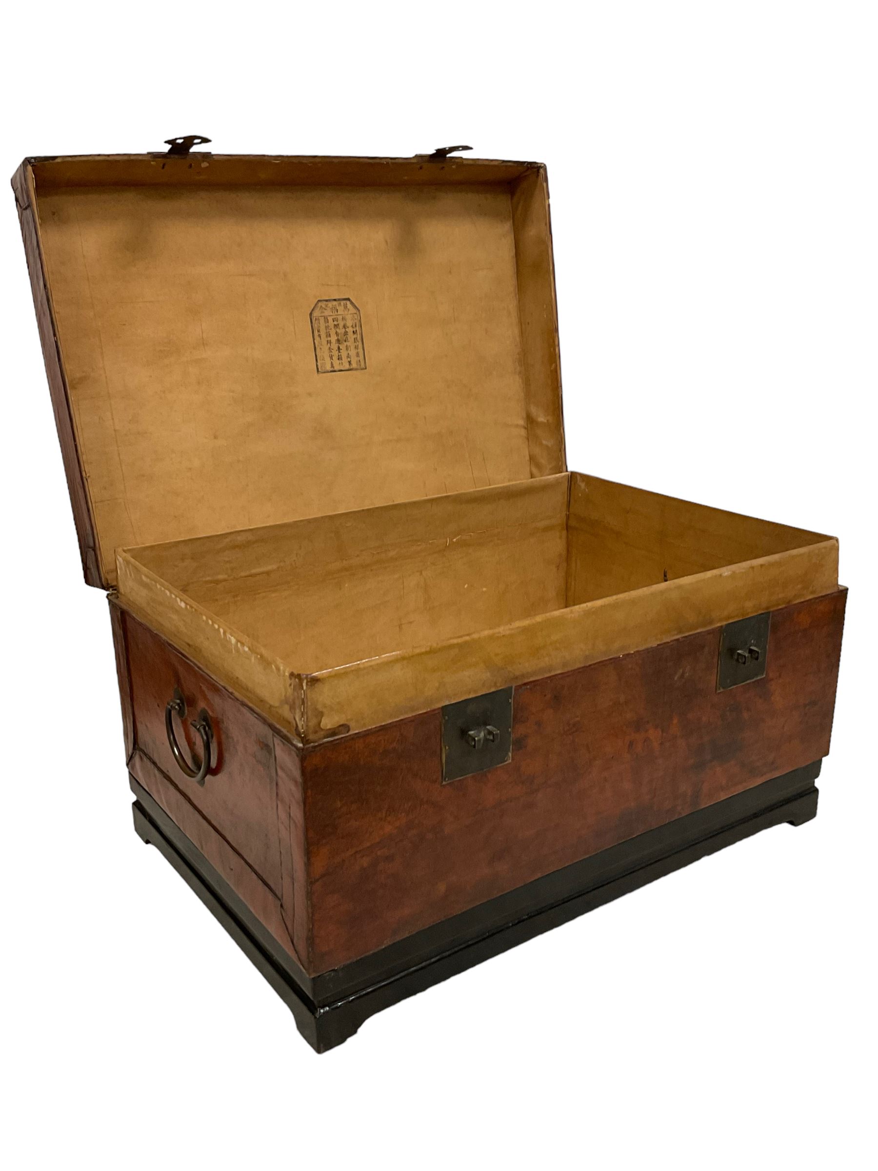 Chinese leather bound and wooden trunk, fitted with metal locks and twin carrying handles, on ebonised stand 