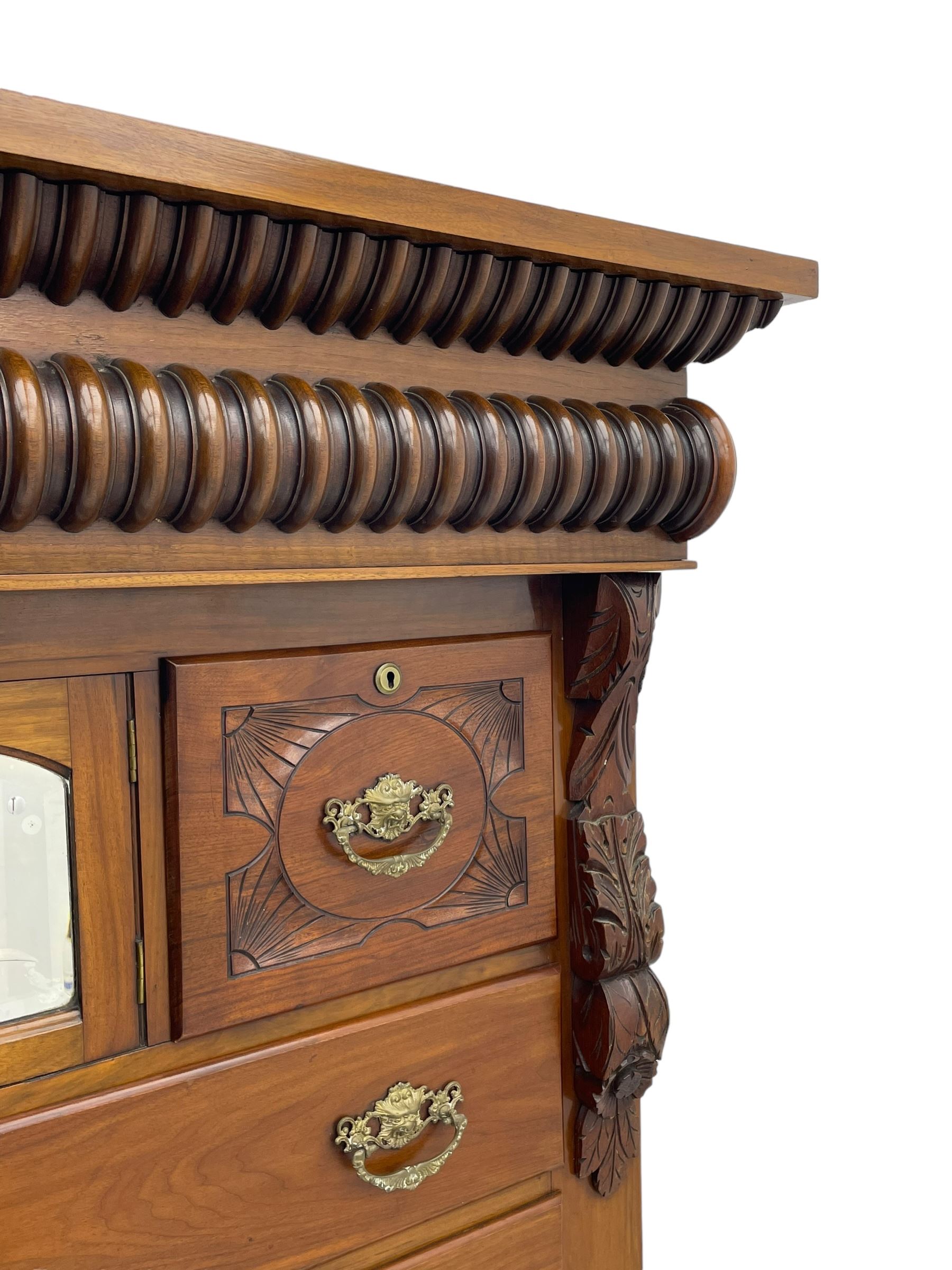 Late Victorian walnut Scotch chest, projecting cornice with turned quarter column mounts over matching half column to frieze, fitted with two upper short drawers with central cupboard, bevelled mirror glazed cupboard door, four graduating drawers below, foliage and flower head carved brackets to the uprights, panelled sides, chamfered plinth on turned feet