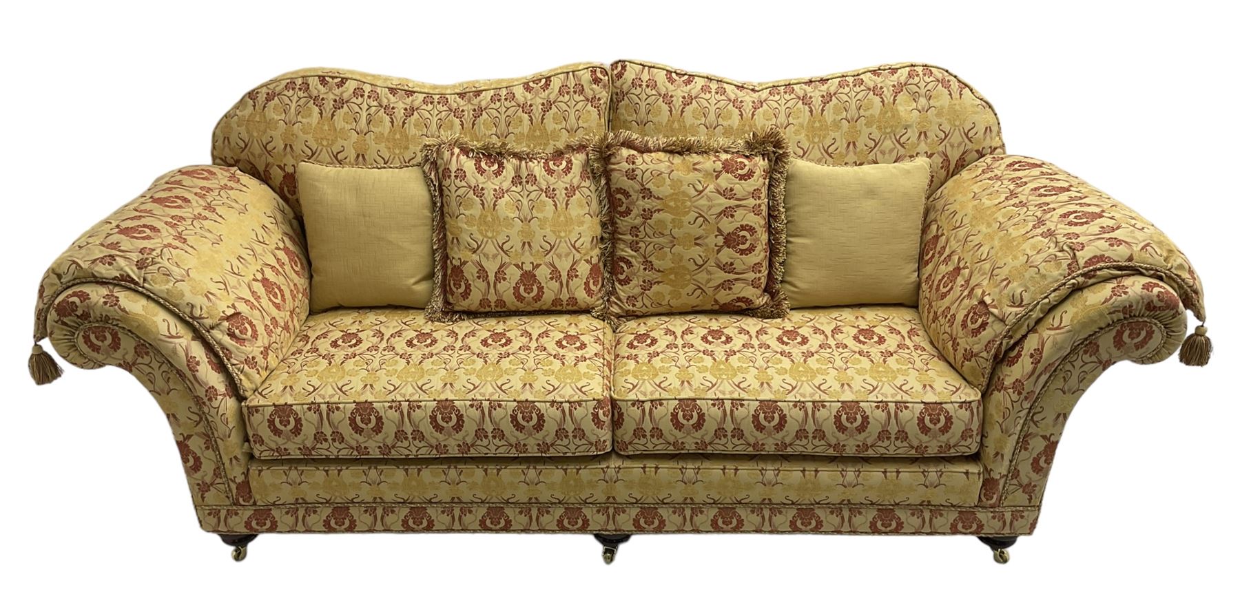 Steed Upholstery Ltd. - 'Lincoln' three-seat sofa upholstered in gold 'Olympia' floral pattern corded and tasselled fabric, together with scatter cushions and arm covers, on turned feet with brass castors