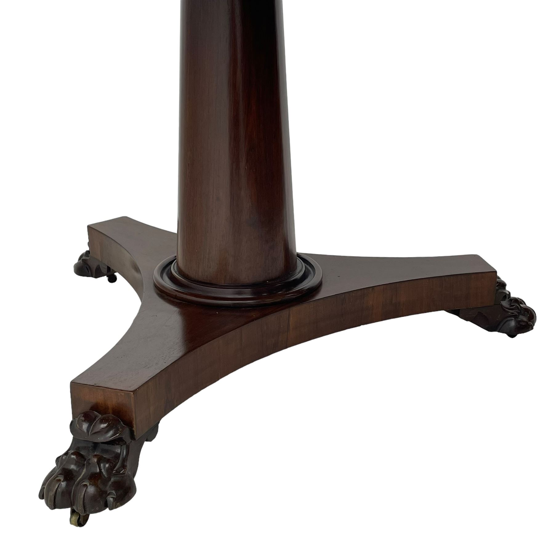 Mid-19th century rosewood breakfast or centre table, circular tilt-top on tapered barrel pedestal, concaved triangular platform, on carved paw feet with castors 