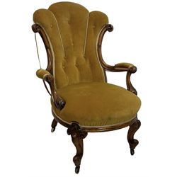 19th century walnut framed open armchair, scallop shaped back with c-scroll uprights, upholstered in yellow buttoned velvet fabric with sprung seat, arm terminals carved with acanthus leaves, raised on scrolling cabriole supports with castors