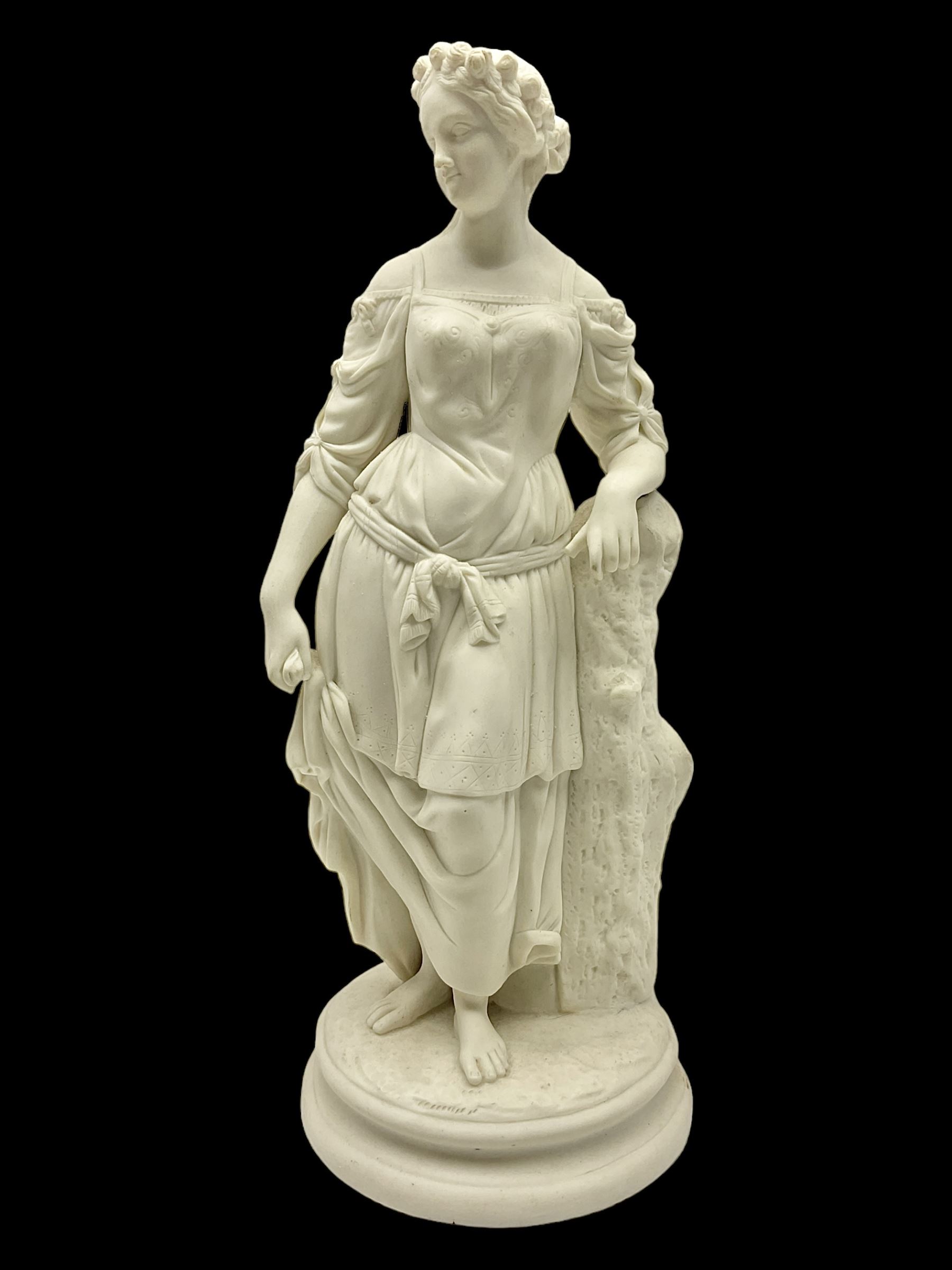 Parian figure modelled as a female in classical dress leaning upon a tree stump, H36cm