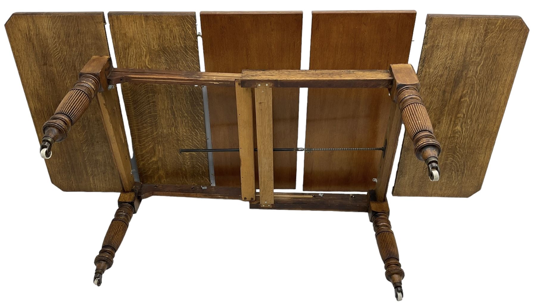 Late Victorian oak telescopic extending dining table, rectangular moulded top with canted corners, three additional leaves, on turned and reeded supports with brass and ceramic castors