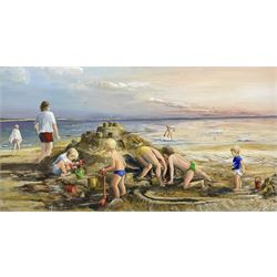 Glenys Bintley (Northern British 20th Century): Children Building a Sandcastle, oil on board signed, artists address label verso 34cm x 64cm