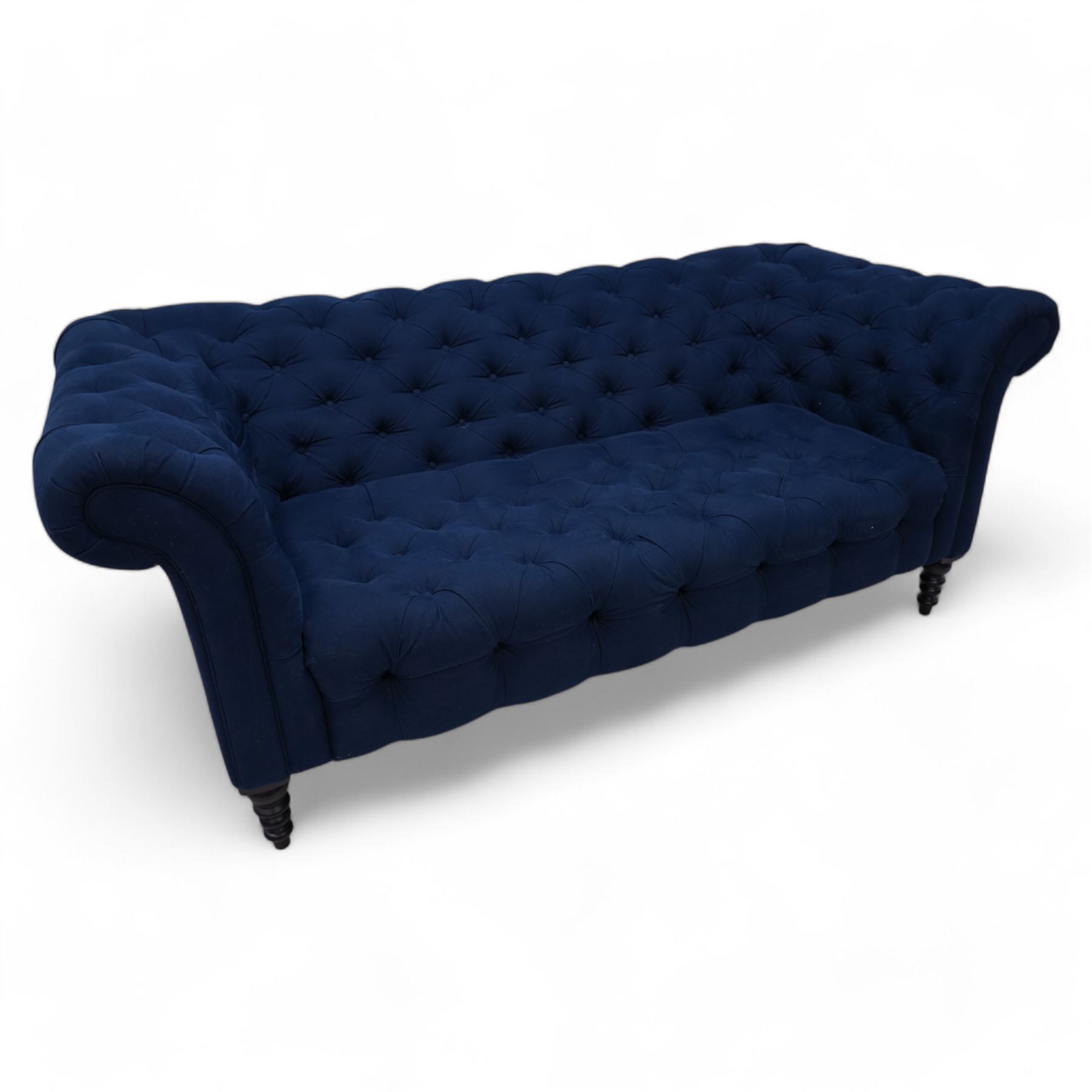 Chesterfield two-seat sofa, traditional shape with rolled arms, upholstered in deep blue buttoned fabric, on black finish turned front feet 