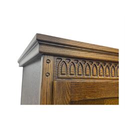 Jacobean design oak double wardrobe, projecting cornice over Gothic arched tracery carved frieze, twin panelled doors with linenfold relief carved detailing, on plinth base