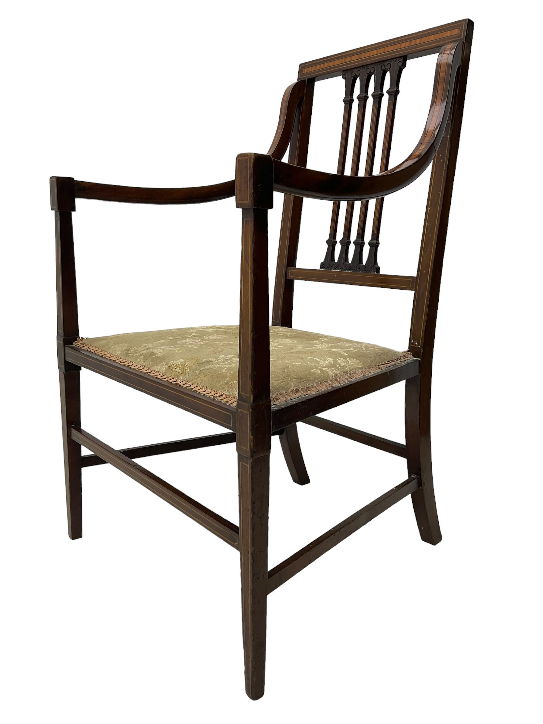 Edwardian satinwood inlaid mahogany elbow chair, the bar back over four vertical rails with foliate and scroll carved decoration, curved and down-swept arms, on square tapering supports united by stretchers 