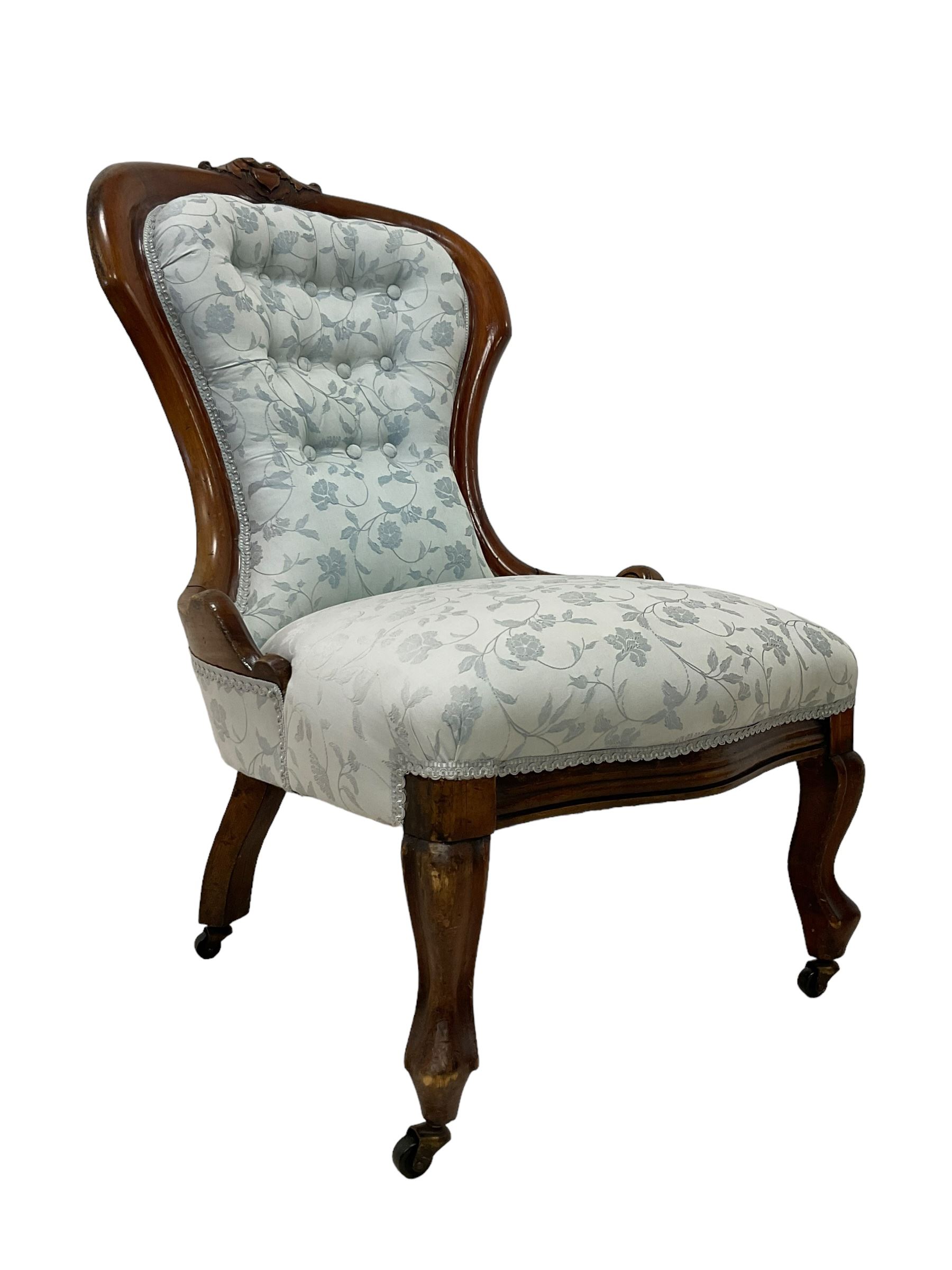 Victorian walnut nursing chair, the curved cresting rail carved with central cartouche and scroll leaves, upholstered in pale blue fabric decorated with trailing floral design, on cabriole front feet 