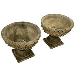 Pair of composite stone garden urn planters, acanthus leaf garland rim over foliate decorated body, stepped foot on square base