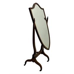 S. & H. Jewell - Edwardian mahogany cheval dressing mirror, shield shaped bevel edged mirror plate within an inlaid mahogany frame, supported by a pair of curved uprights topped with finials and terminating in a scroll design with floral inlay, the reverse bearing makers plaque, standing on four shaped supports fitted with brass castors