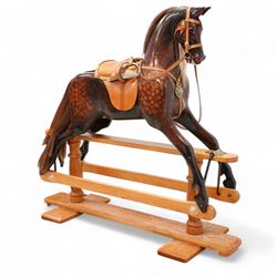 Carved wooden rocking horse, painted in dapple brown with glass eyes, fitted with tan leat...