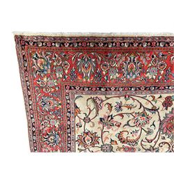 Persian Sarough ivory ground rug, the field decorated with curled leafy branches and palmettes, crimson ground border decorated with further palmettes and floral sprays, within guard stripes 