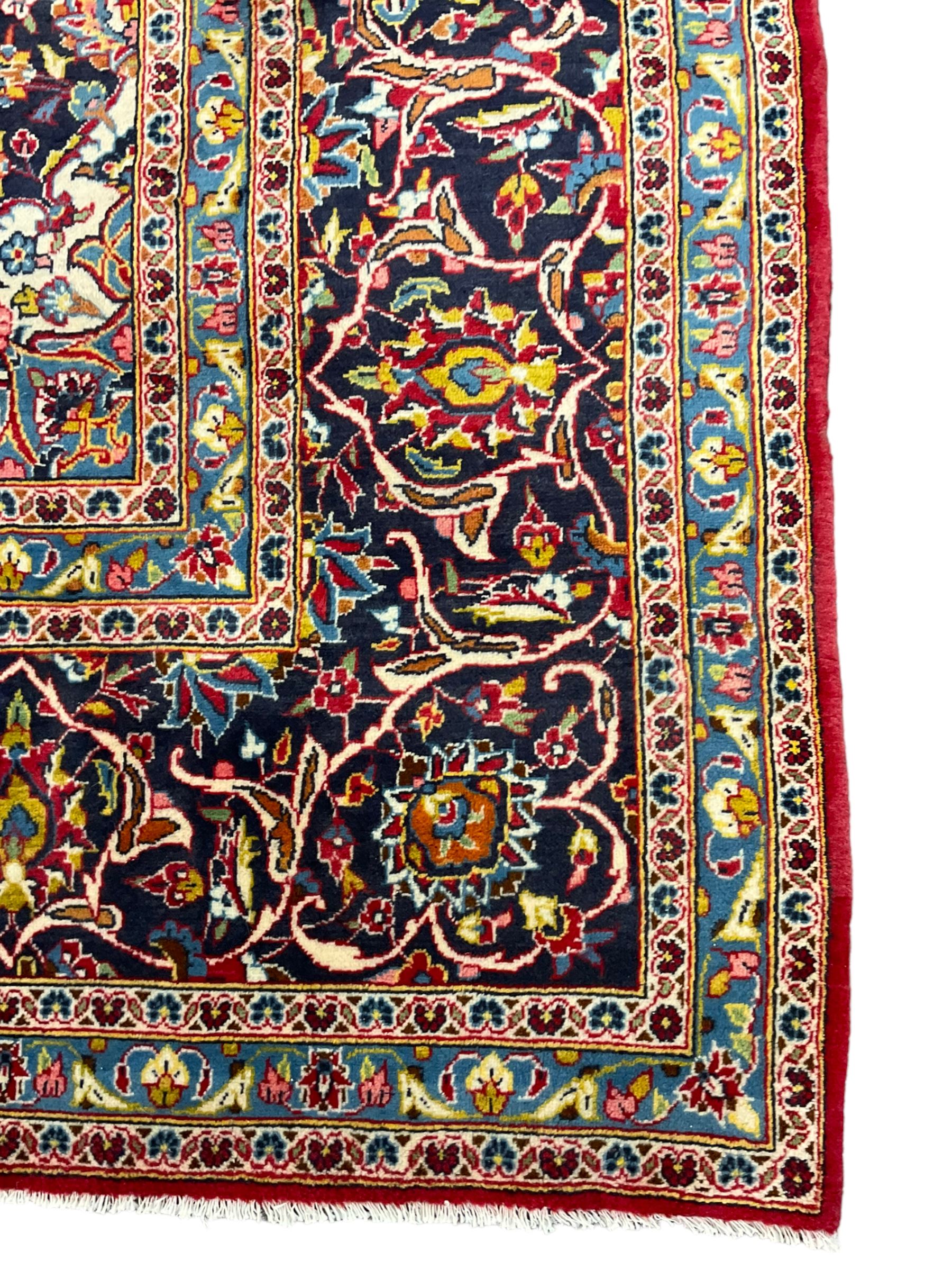 Persian Kashan crimson ground carpet, floral design central medallion surrounded by trailing leafy branches and stylised plant motifs, multi-band border with repeating floral design