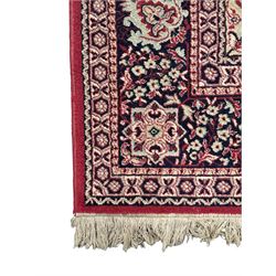 Persian Heriz design red ground carpet, the field decorated with a central star-shaped medallion surrounded by geometric floral motifs and angular vine patterns, the spandrels highlighted with palmette designs, the main border featuring a series of stylised rosettes and leaves against a dark blue ground, enclosed by multiple guard stripes with alternating floral and geometric motifs