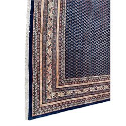 Large North-West Persian Arrak indigo ground carpet, the field decorated all-over with small Boteh motifs, multiple band border decorated with repeating geometric designs