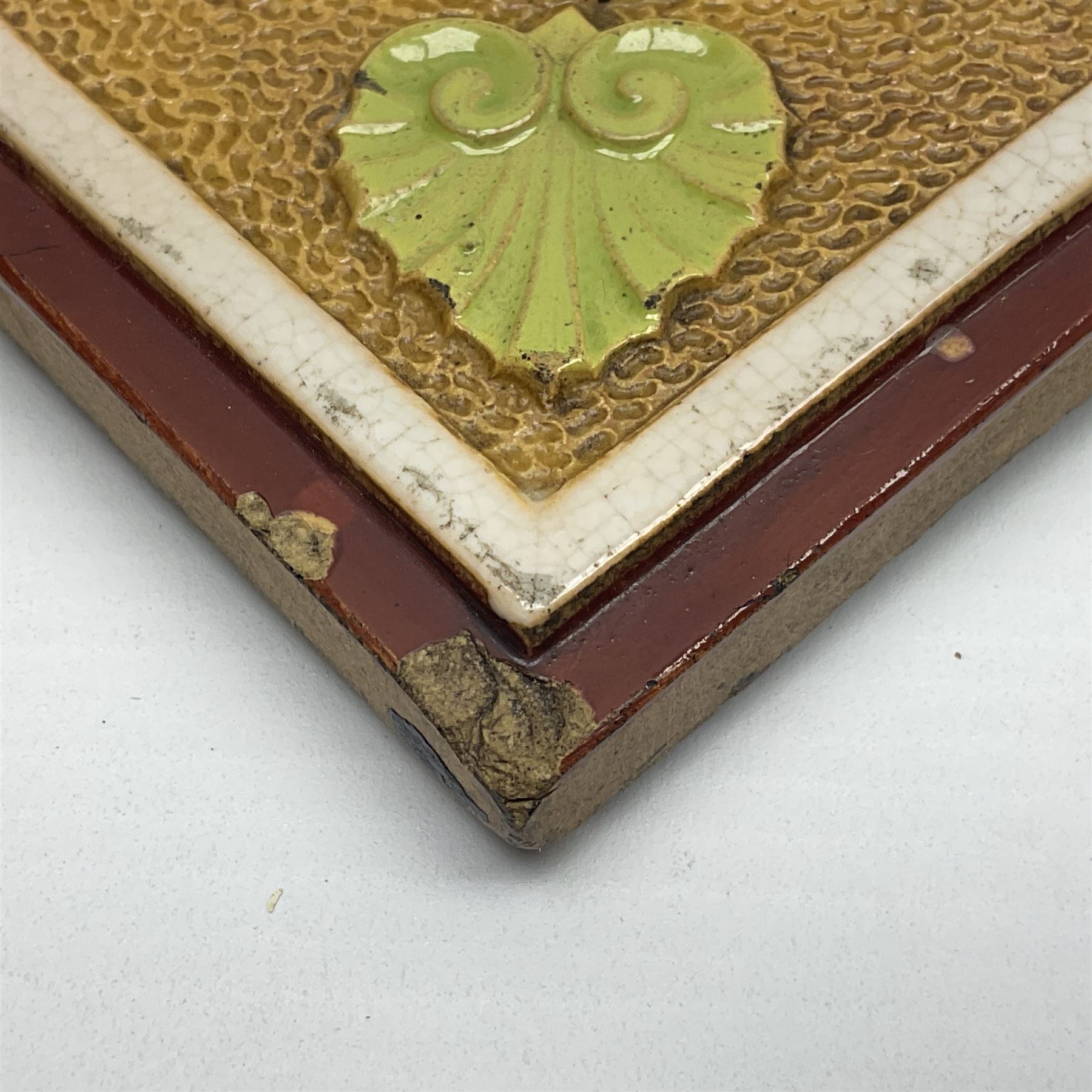 19th century Minton & Co majolica tile, decorated in relief with a bird upon a fruiting branch against a blue ground, with textured ochre border and anthemion to each corner, impressed mark verso, H19.7cm