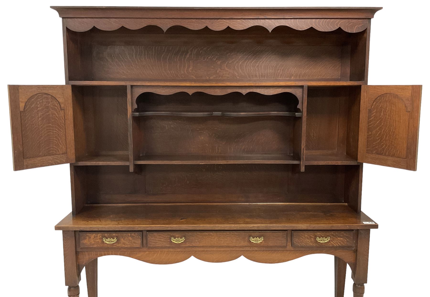 Early 20th century Georgian design oak dresser, projecting cornice with shaped apron over a three-tier plate rack with flanking fielded spice cupboards, the base fitted with three drawers, on turned supports