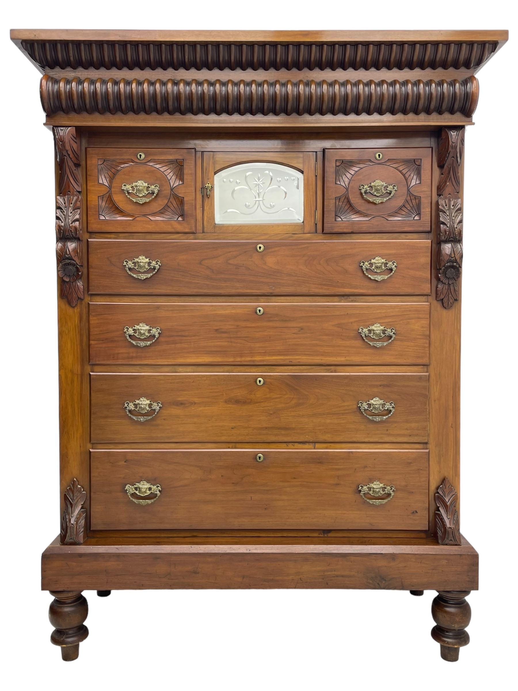 Late Victorian walnut Scotch chest, projecting cornice with turned quarter column mounts over matching half column to frieze, fitted with two upper short drawers with central cupboard, bevelled mirror glazed cupboard door, four graduating drawers below, foliage and flower head carved brackets to the uprights, panelled sides, chamfered plinth on turned feet