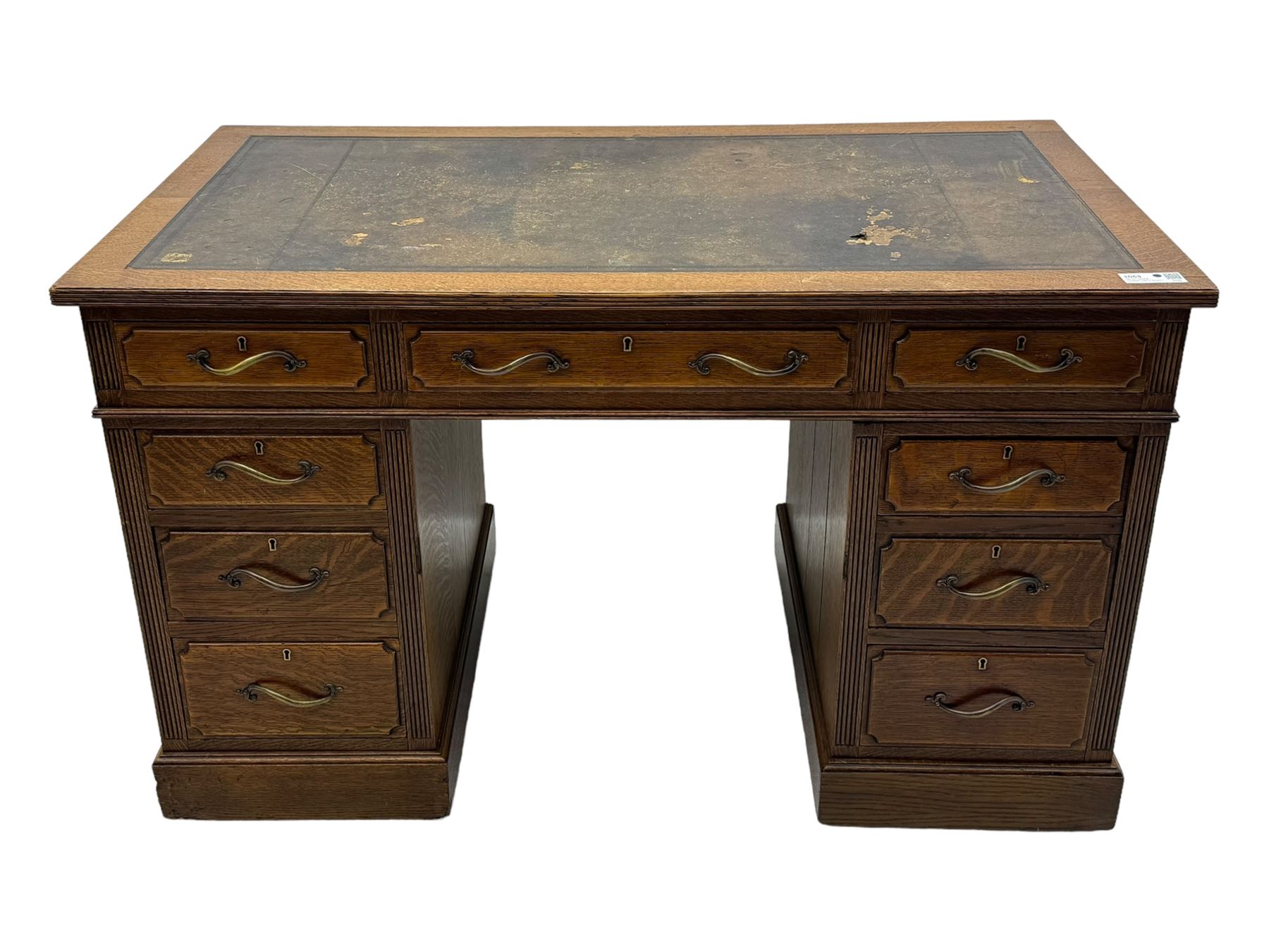 20th century oak twin pedestal desk, rectangular top with inset leather writing surface, fitted with nine drawers with chamfered edges to the raised panels, each with curved brass handles with scroll ends and keyholes, fluted detailing to the top and between the drawers, on moulded plinth base with castors