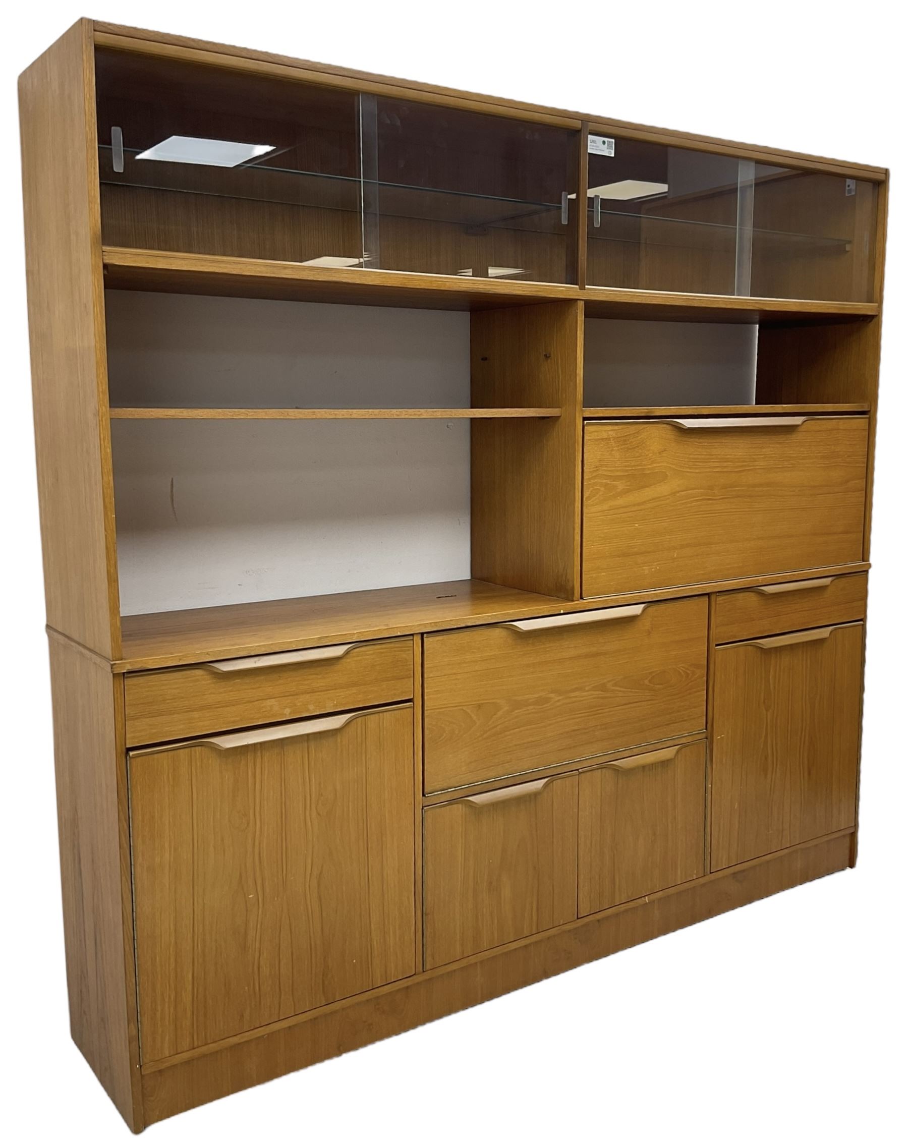 Mid-20th century teak sectional wall unit, combination of cupboards and drawers, raised sliding glass doors