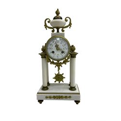 French - early Edwardian 8-day gilt metal and white marble clock garniture c1910, drum head case surmounted by an urn with cast side scrolls, supported by four pillars on a rectangular stepped plinth with recessed feet, white enamel dial with Arabic numerals, garland swags and gilt hands, with a sunburst pendulum and twin-train countwheel striking movement, striking the hours and half hours on a bell. With a pair of three light, two branch candelabra on scroll-cast branches. With key and pendulum.