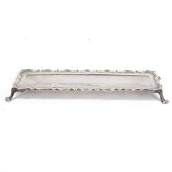 Edwardian silver pen tray, of rectangular form, with shaped rim and central recess, upon f...