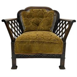 Early 20th century three-piece bergère suite - three seat sofa (W177cm, H82cm, D75cm); pair of matching armchairs (W84cm); single caned back with 'cock-pen' panelled arms, upholstered in foliate pattern fabric, blind fretwork lower frieze over square feet 