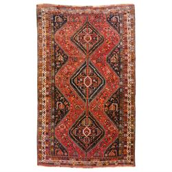 Persian Shiraz crimson ground rug, triple pole medallion surrounded by small stylised moti...