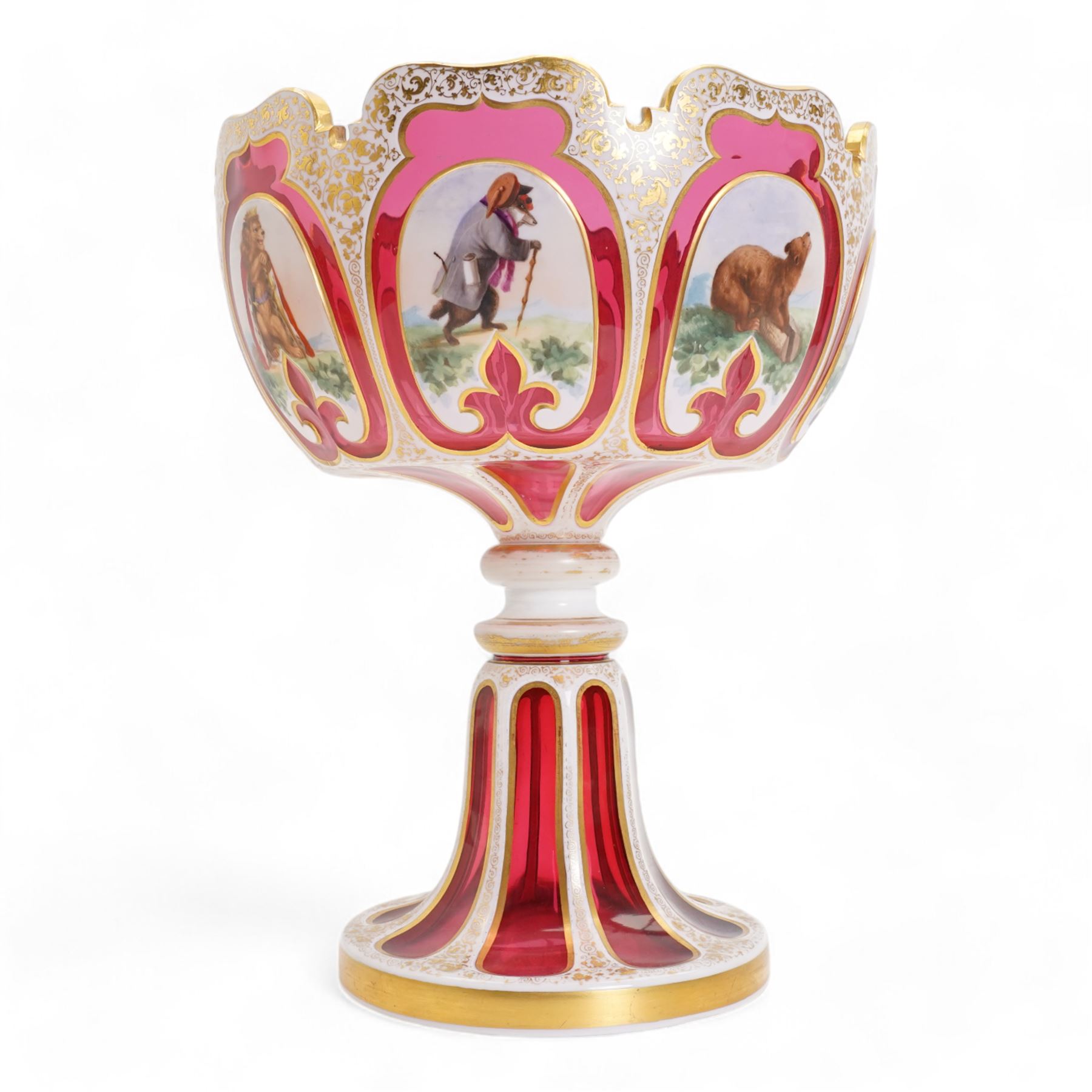 Late 19th century Bohemian white overlaid cranberry glass pedestal bowl, with fancy scalloped rim and cut with oval and fleur de lis shaped panels, each enamelled with 'Reynard the Fox' anthropomorphic animals, after the illustrations by Wiilhem Von Kaulbach,  within gold borders with gilt scrolling decoration, supported by a slice cut circular spreading foot with further gilt decoration, H28.5cm x W22.5cm