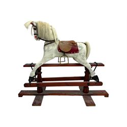 Mid 20th century rocking horse, dappled grey painted horse with applied mane and tail, red leather saddle and bridle accented with brass studs, supported by a stained wooden frame with turned supports and iron brackets, mounted on rockers