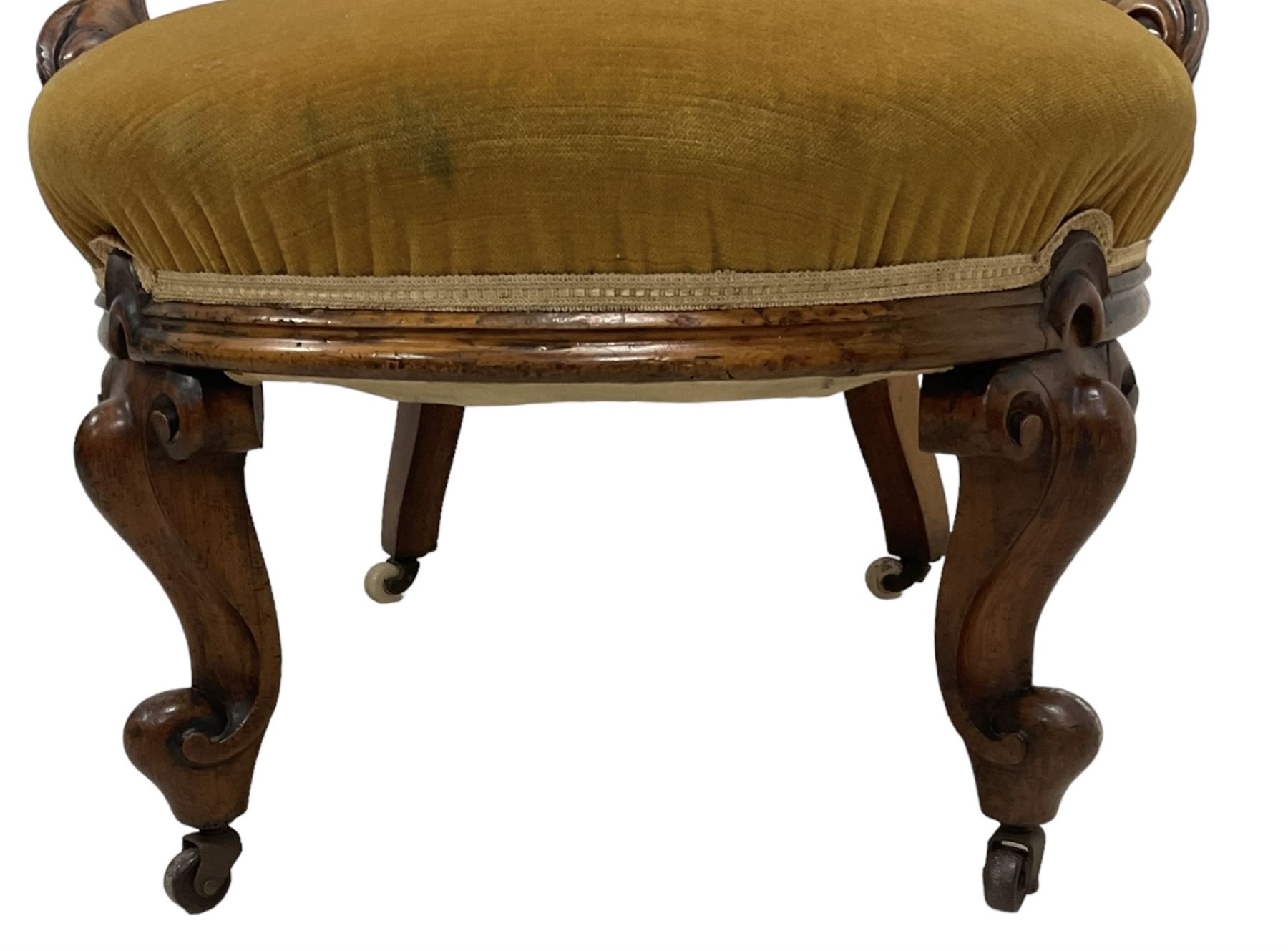 19th century walnut framed open armchair, scallop shaped back with c-scroll uprights, upholstered in yellow buttoned velvet fabric with sprung seat, arm terminals carved with acanthus leaves, raised on scrolling cabriole supports with castors