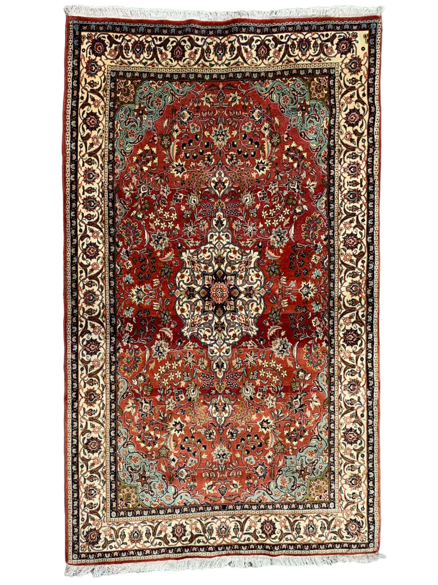 Small Persian Kashan crimson ground rug, the central interlaced medallion surrounded by scrolling foliate branches and stylised plant motifs, scrolling border with guard bands