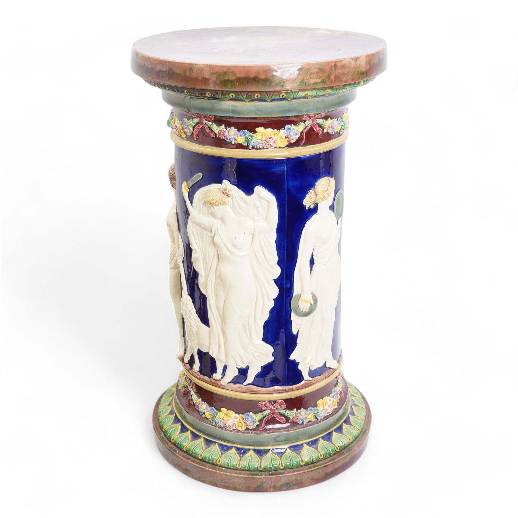 Late Victorian Copeland Majolica pedestal, circa 1850 - 1870, the cylindrical column moulded in relief with a frieze of Classical figures in cream on a cobalt glazed ground, the borders with coloured flower garlands and tortoiseshell mottled top, H62cm x D35cm