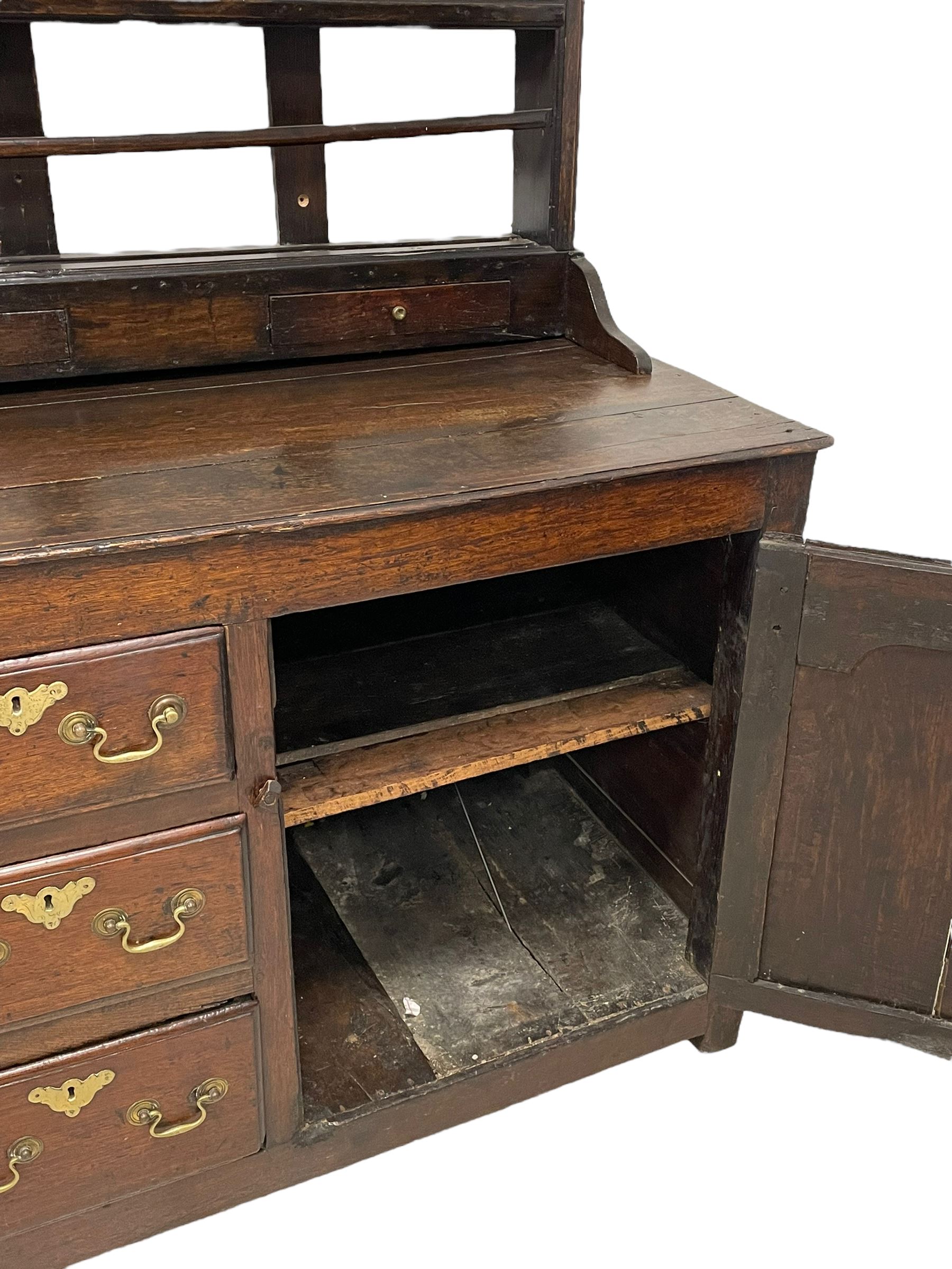 18th century oak dresser, projecting cornice over three heights plate rack with three small drawers, rectangular ovolo-moulded top over three central drawers and two flanking cupboards, enclosed by fielded panelled doors, on stile supports 