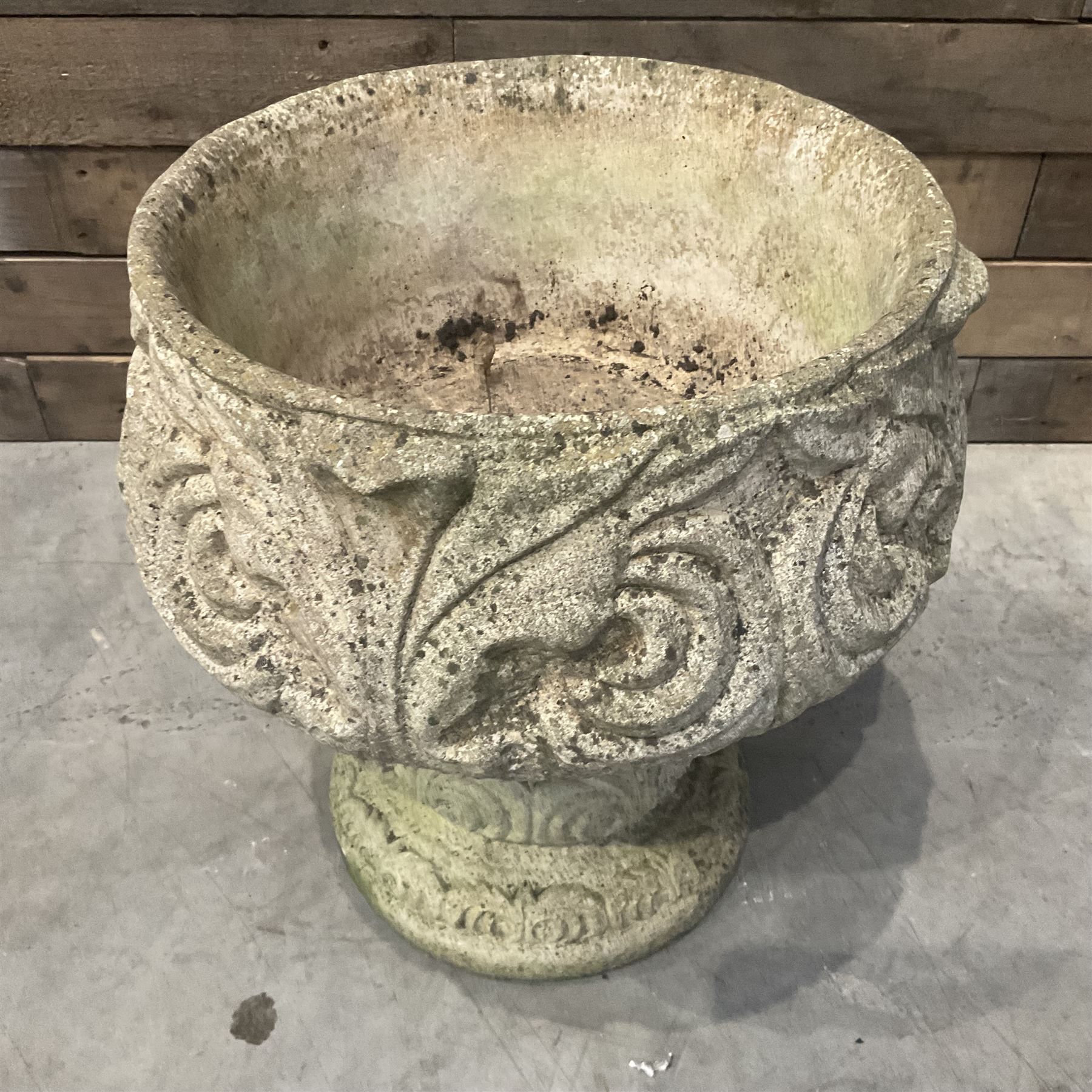 Cast stone circular garden urn decorated with scrolling foliate relief pattern