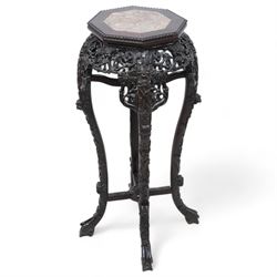 Early 20th century Chinese hardwood and marble top jardiniere or urn stand, octagonal top with central marble inset and bead edge, over pierced and carved foliate rails, the cabriole supports carved with trailing vines and protruding foliate decoration, united by X-stretcher on shaped claw feet