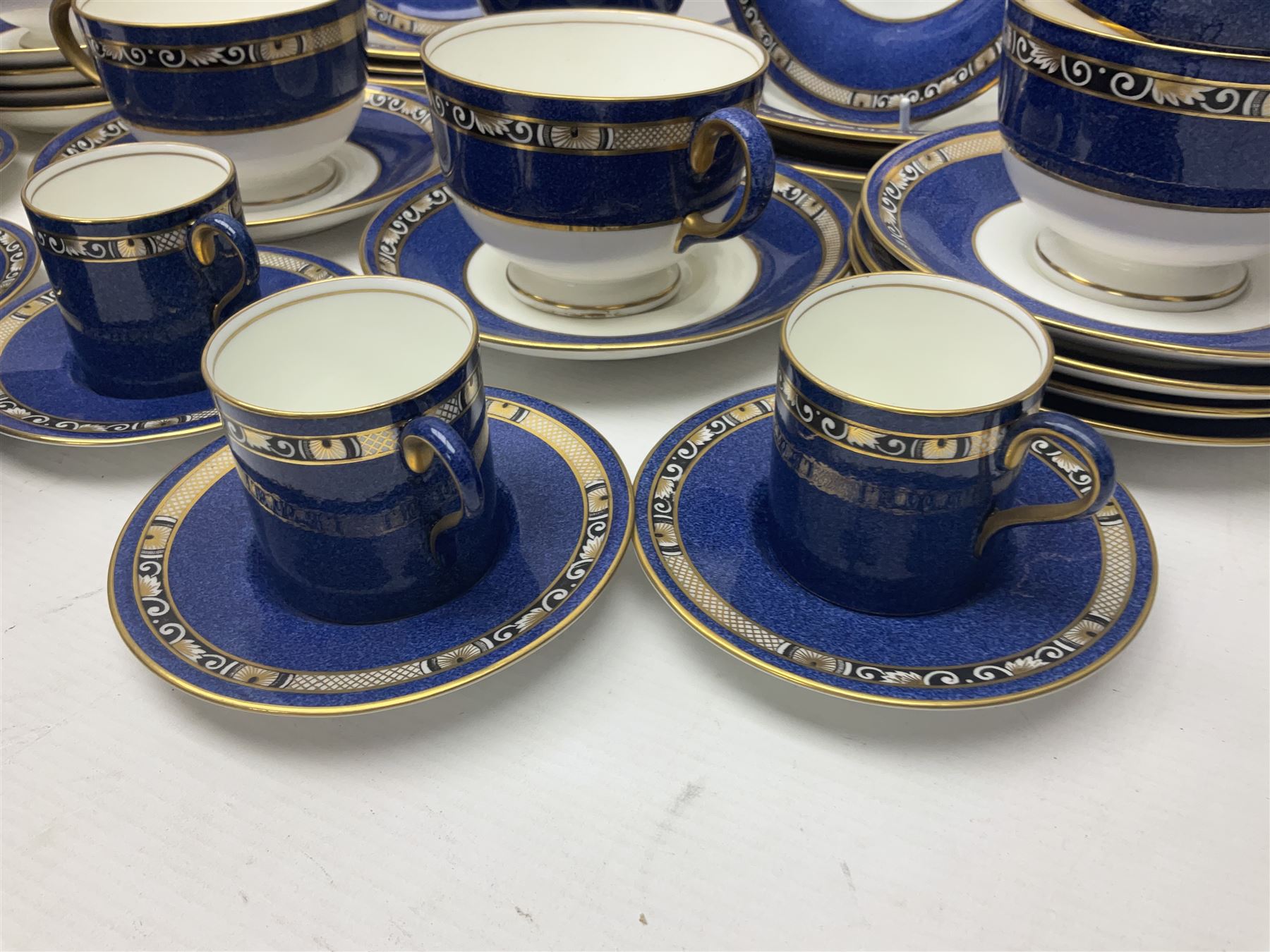 Wedgwood part tea and coffee service, comprising coffee pot, six coffee cans with five saucers, seven teacups with ten saucers and seven side plates, each decorated with floral bouquet to centre, in a gilt and speckled blue border, pattern x9933, with printed mark beneath