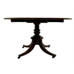 George III mahogany breakfast table, oval tilt-top on turned column with four splayed supports, fitted with brass cups and castors 