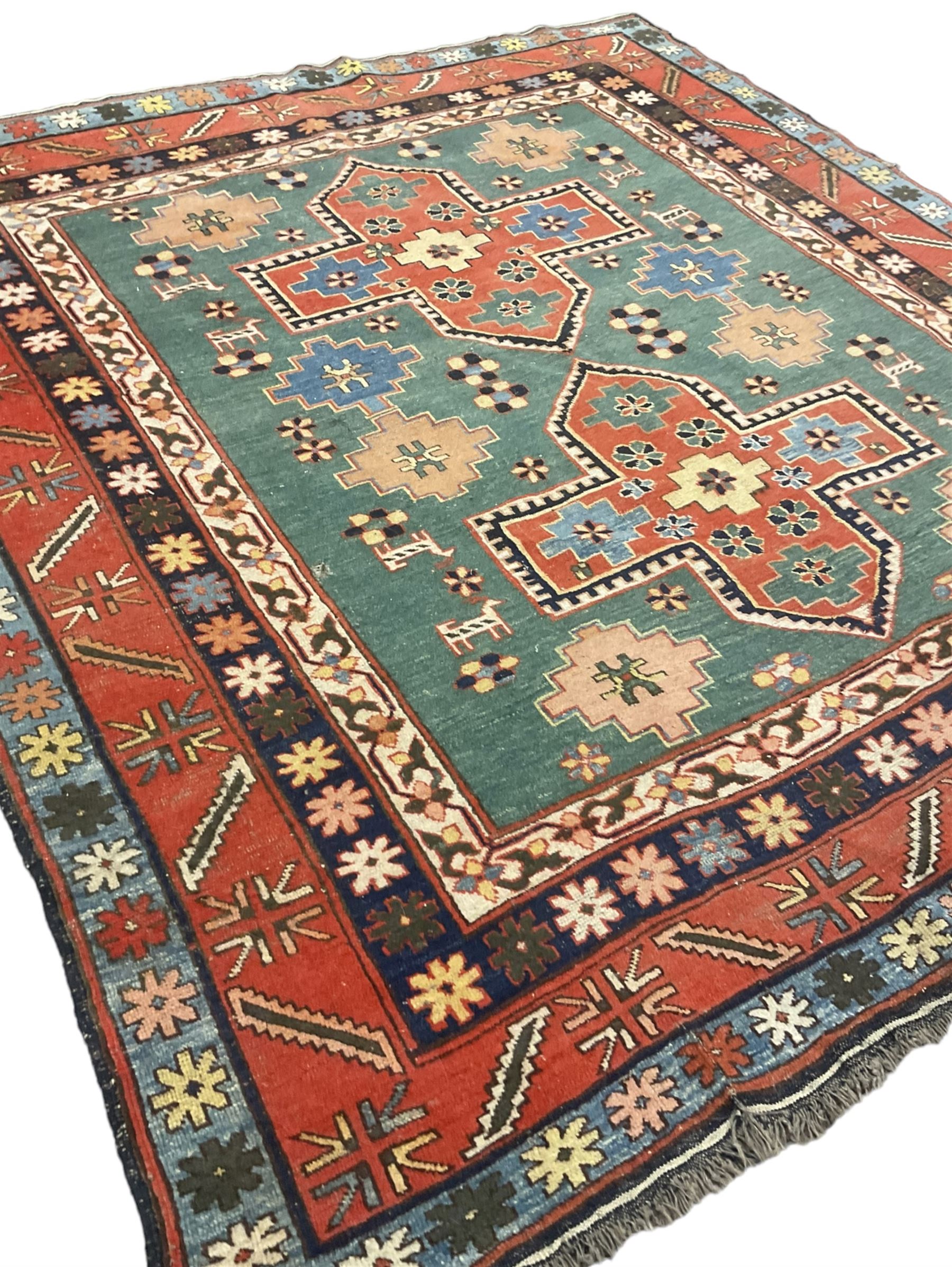 Caucasian turquoise ground rug, two medallions on a field decorated with stylised animal and geometric motifs, the guarded border decorated with further geometric motifs