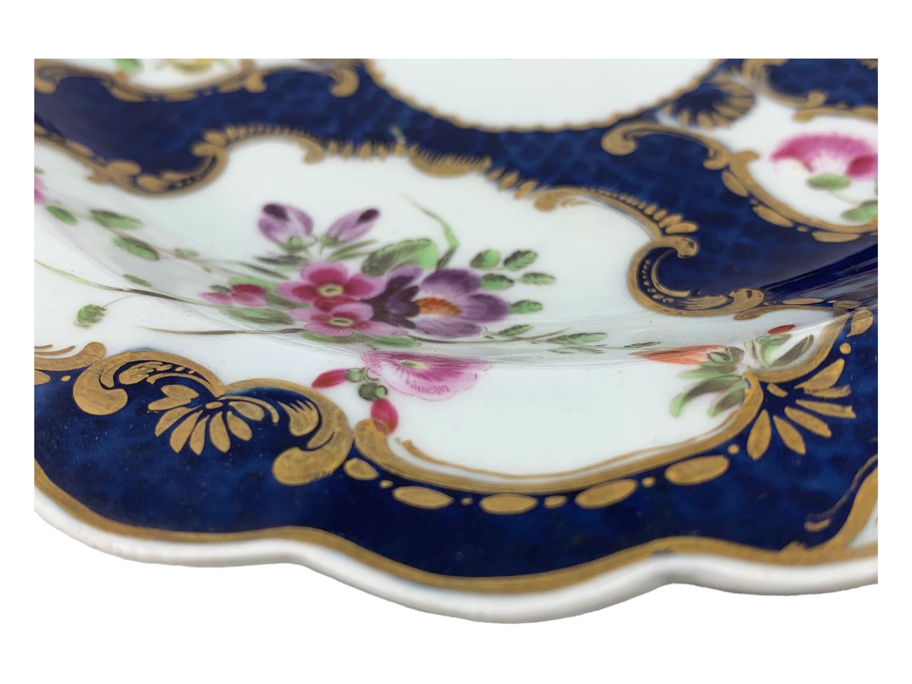 18th century Worcester tea caddy, of oval form and painted in the Kakiemon palette with reserves of flowers against a blue scale ground, H14cm together with a similar Worcester circular dish, painted with floral sprays, within a scalloped edge, blue crescent mark beneath, D19cm (2)