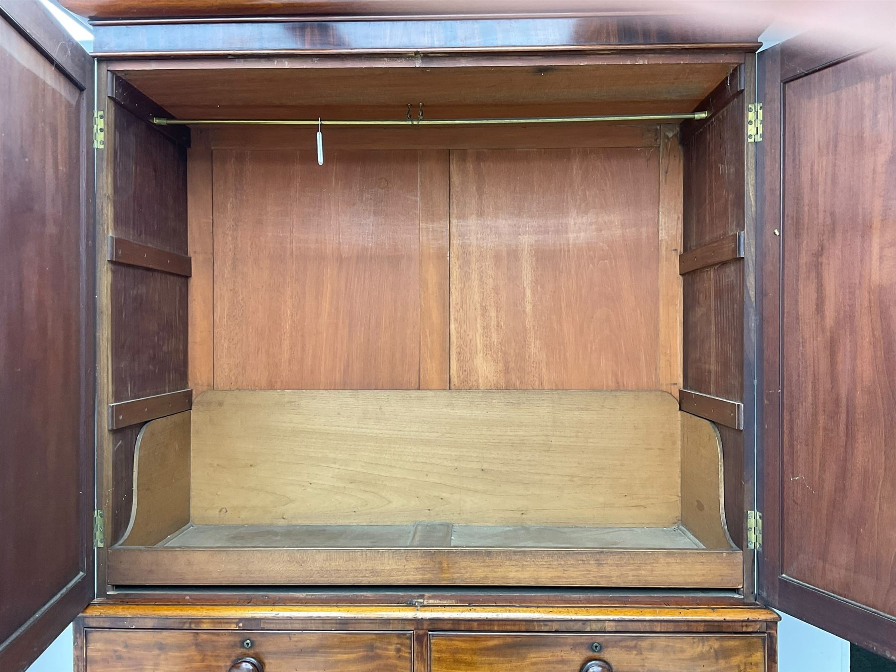 Victorian figured mahogany linen-press, projecting moulded cornice over two arch panelled doors, fitted with two short and two long cock-beaded drawers, on turned feet