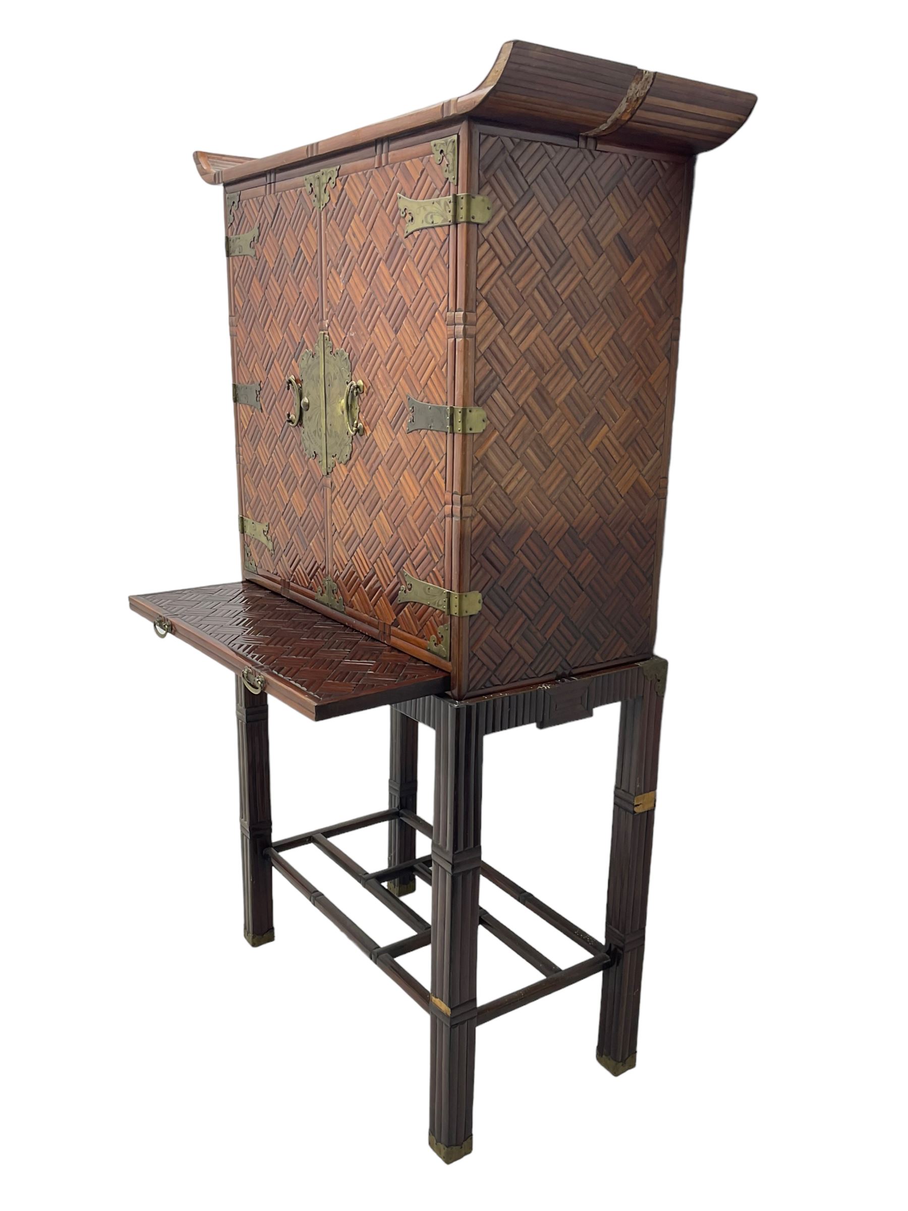 Chinese design bamboo and wood altar cabinet on stand, parquetry lattice-work bamboo, two doors with engraved metal fixtures enclosing drawers and shelf, fitted with slide, the stand pm square supports joined by a series of geometric stretchers